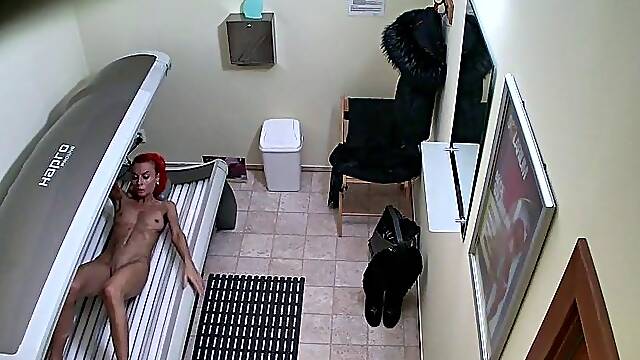 Red MILF rubs her pussy in solarium